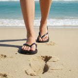 Black sandals with metallic straps on a sandy surface