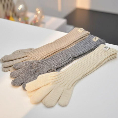Three pairs of long gloves in beige, grey, and white on a white surface