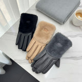 Three pairs of gloves in black, beige, and grey on a marble surface with a cup of coffee and scarf