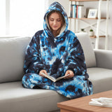 Absorbed in an open book, wearing stormy blue and charcoal marbling with the hood raised