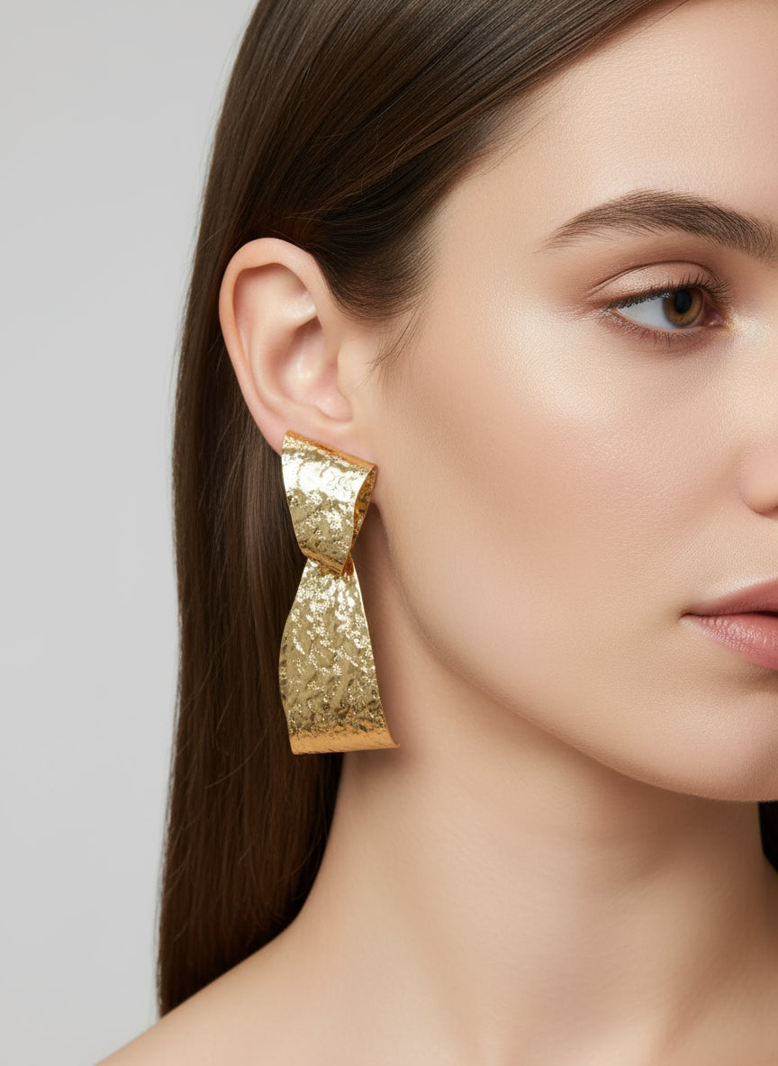 Gold timeless charm earring worn by a model on a plain background