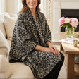 Woman wearing a leopard print puncho sitting on a couch in a cozy living room