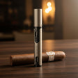 Silver cigar lighter and unlit cigar on a wooden surface with a warm background
