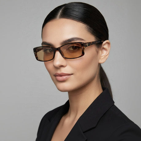 Woman wearing brown tortoise slim sunglasses with a grey background