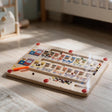 Wooden train magnetic maze with numbered carriages, coloured beads and an orange pen on the floor