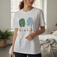 Woman wearing a white t-shirt with nature-themed design in a bright room