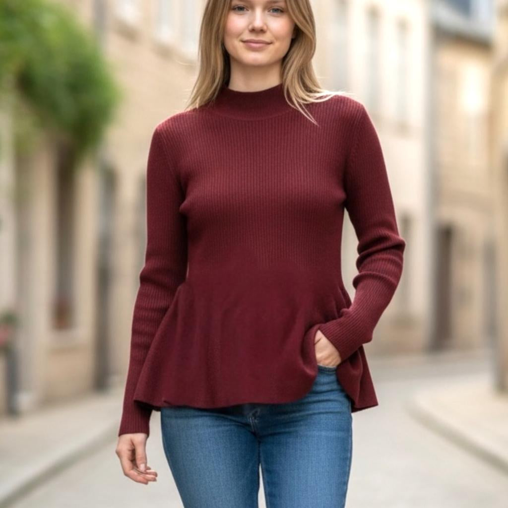 Red mock neck peplum top in fitted rib knit, flared at the waist, worn on a city street