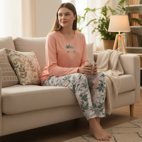 Woman wearing a peach floral cotton pyjama set while relaxing on a couch with a mug - Jack Gifts Online Lebanon