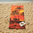 Beach towel with palm tree and sunset design on a sandy beach