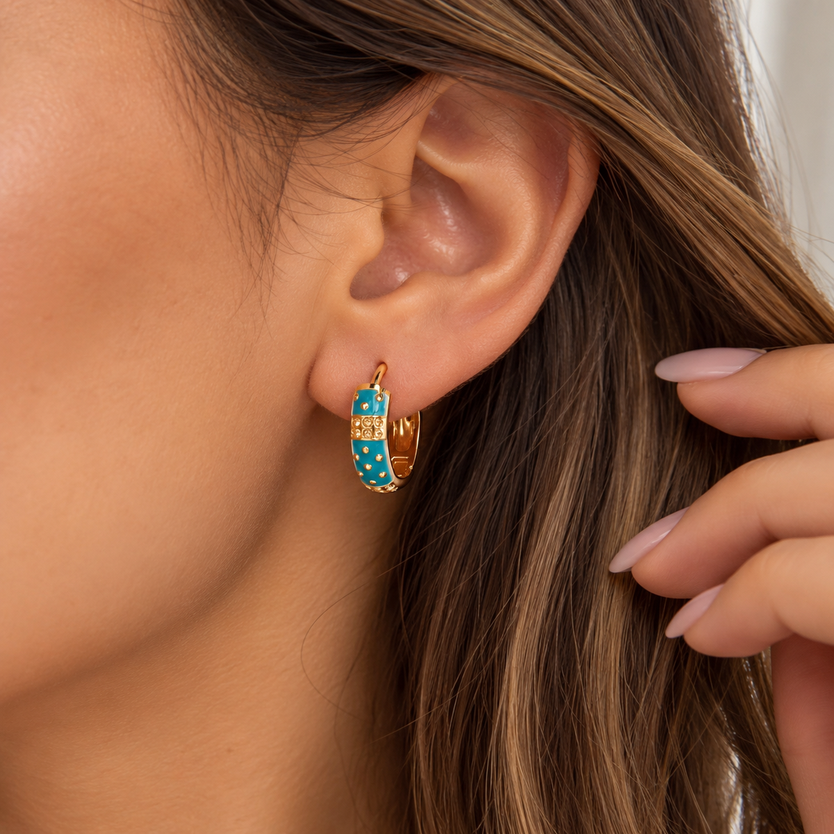 Turquoise enamel hoop earring with gold dots and a textured gold band worn on the ear