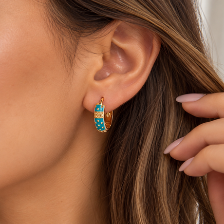 Turquoise enamel hoop earring with gold dots and a textured gold band worn on the ear