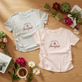 Two t-shirts with a succulent design on a wooden surface with plants and flowers.