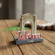 Standing souvenir with the Roman arch of Tyre in cream stone behind a red Lebanon