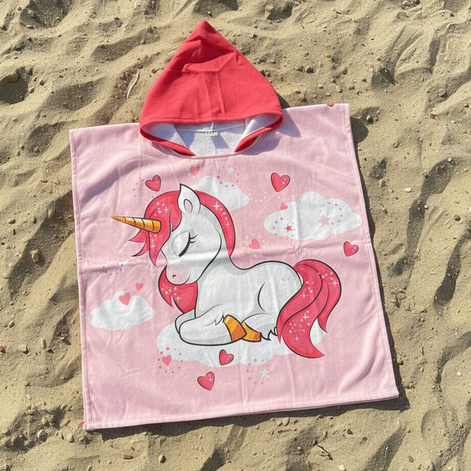 Pink hooded poncho with unicorn design on sand