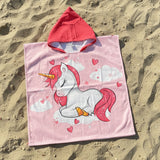 Pink hooded poncho with unicorn design on sand
