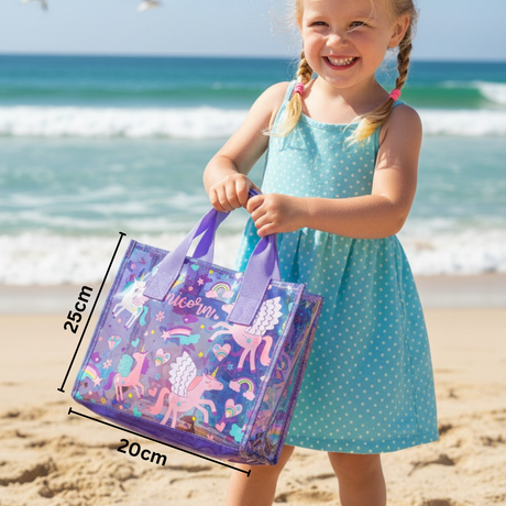 Girl in a blue polka dot dress carrying a unicorn print clear tote, marked 25cm tall and 20cm wide