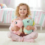 Girl holding a pink and a mint unicorn, both with glitter horns and rainbow manes