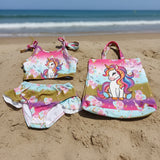 Children's swimsuit set with unicorn design and matching tote bag on a gray background