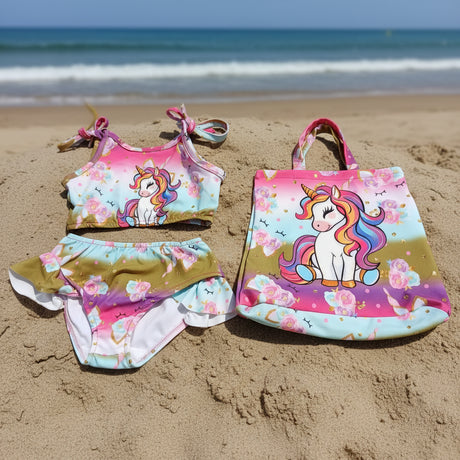 Children's swimsuit set with unicorn design and matching tote bag on a gray background