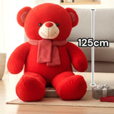 Red teddy bear seated facing forward with a pink scarf and checked ear patches