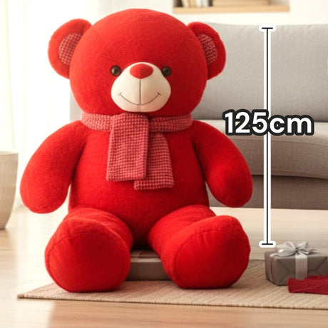 Red teddy bear seated facing forward with a pink scarf and checked ear patches