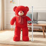 Bright red teddy bear standing with a soft pink knitted scarf around its neck