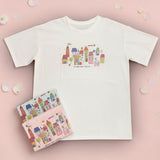 White tshirt with colorful cityscape design on a pink background