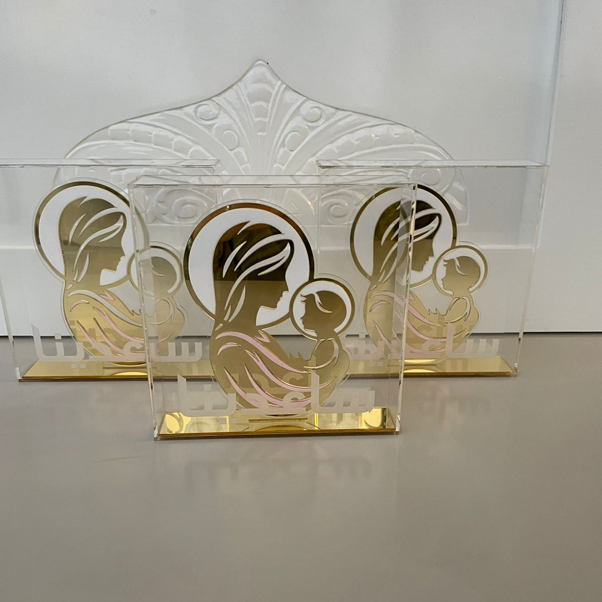 Three of the gold line art panels in a row against a carved white arch panel