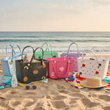 Colorful beach bags and accessories on a sandy beach with ocean view