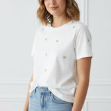 Woman wearing a white t-shirt with small heart patterns and blue jeans on a plain background