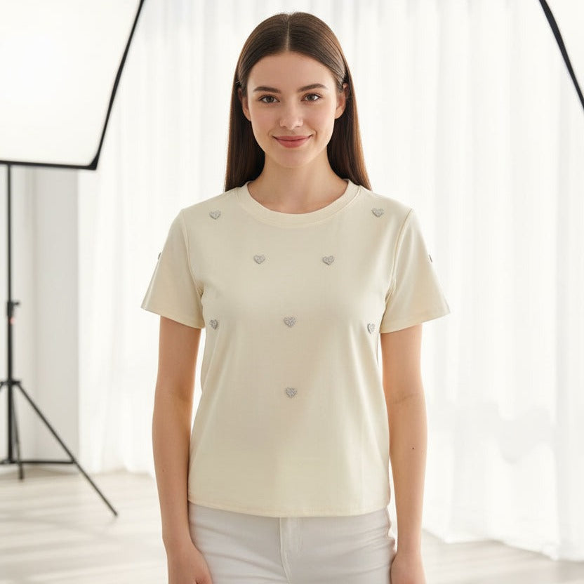 Woman wearing a cream-colored t-shirt with small decorative buttons against a white background