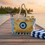 Tote bag with a blue and yellow design on a wooden dock by a body of water.