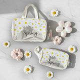 Two clear pouches with floral designs and 'Hello Spring' text, surrounded by flowers on a light background.