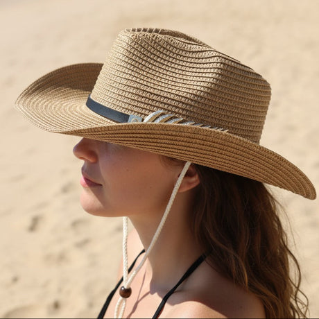 Woman wearing a straw hat on a beach with ocean and palm trees in the background