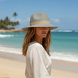 Woman wearing a hat on a beach with ocean and sky in the background