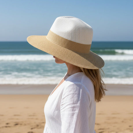 Woman wearing a white hat and dress on a beach with ocean view