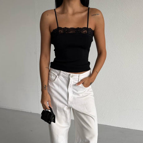 Person wearing a black top and white pants with a plain background