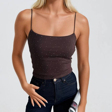 Woman wearing a brown tank top and dark jeans against a light background