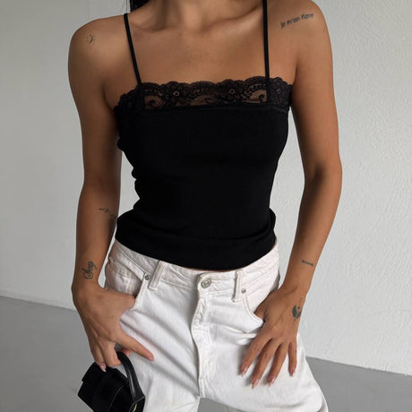 Person wearing a black lace-trimmed top and white pants against a plain background