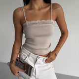Person wearing a beige lace-trimmed top and white pants, holding a magazine.
