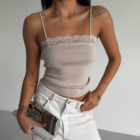 Person wearing a beige lace-trimmed top and white pants, holding a magazine.