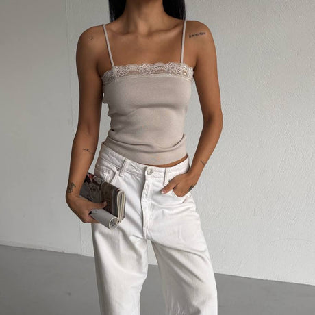 Person wearing a beige top and white jeans against a plain background