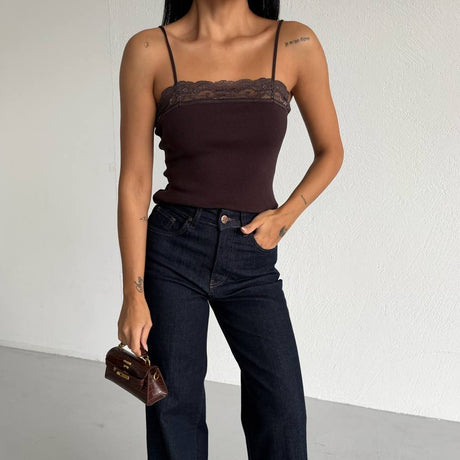 Woman wearing a brown top and dark blue jeans against a white background