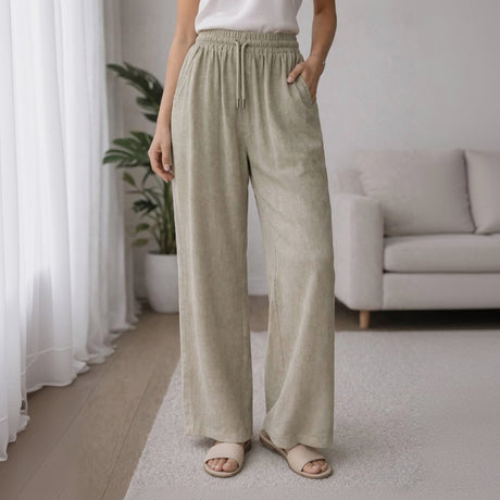 Person wearing light green wide-leg pants in a home setting