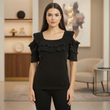 Woman wearing a black ruffled top in an indoor setting