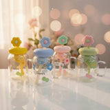 Four transparent jars with colorful flower-shaped lids on a white surface with a blurred background.