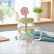 Clear jar with a pink flower-shaped lid on a table with a blurred background