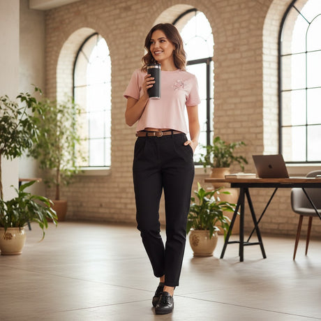 Woman holding a black insulated coffee cup in a modern office setting with large windows and plants.