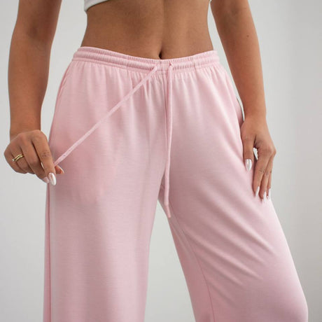 Person wearing pink sweatpants and a white top against a plain background