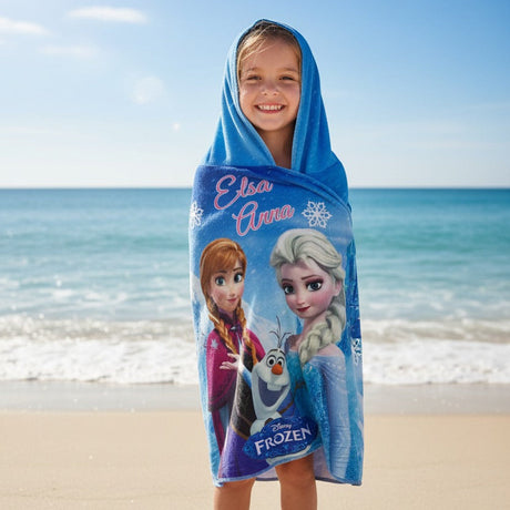 Child wrapped in a Frozen-themed towel on a beach